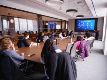 Group of students sit at a very large conference table at Madison Square Gardens offices.